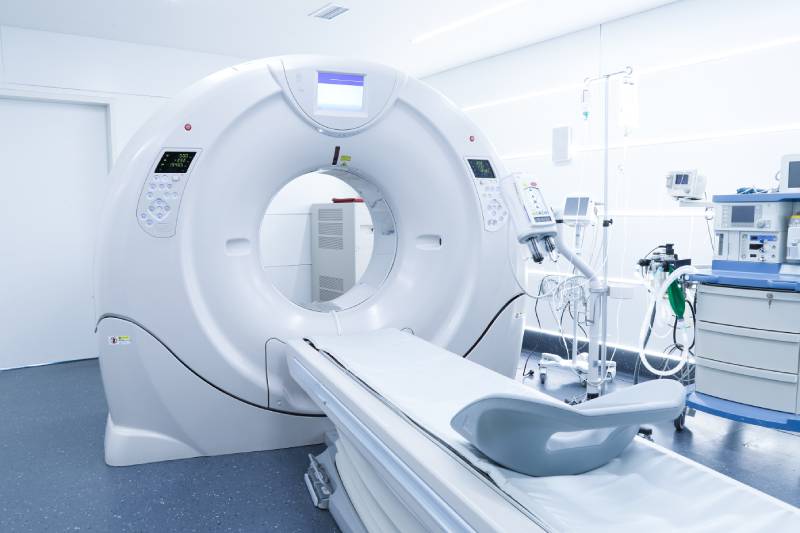A male radiographer preparing the CT scanner in an imaging room.