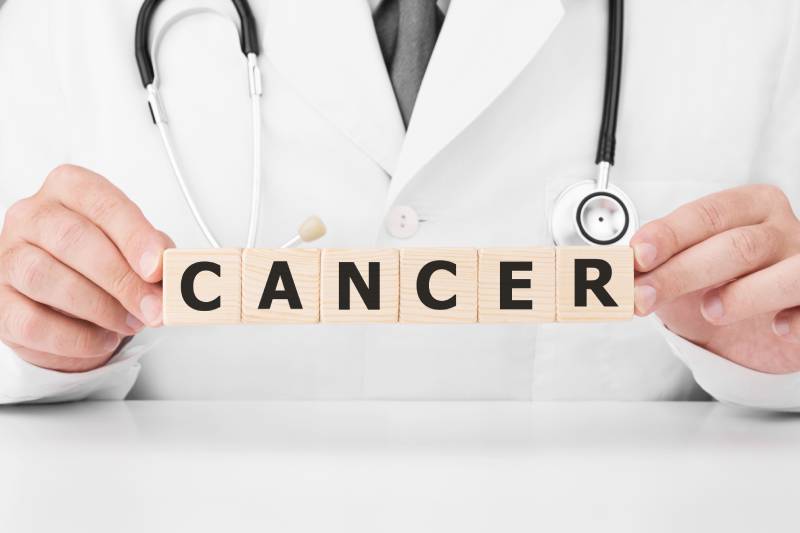 A doctor holding wooden blocks with the word cancer written on it.