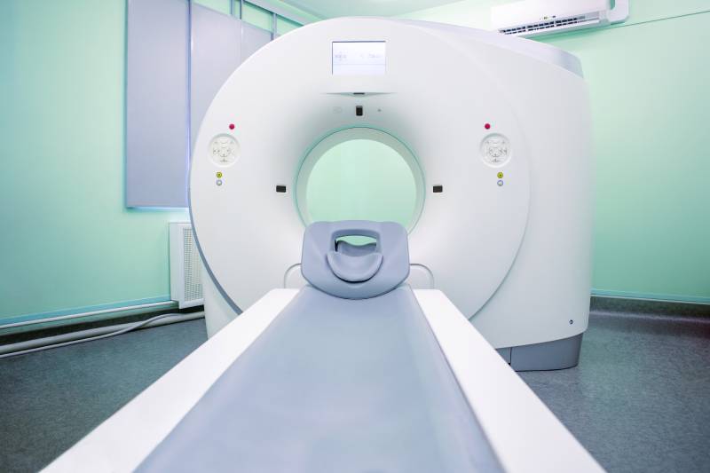 A complete front view of an MRI scanner inside an hospital environment.