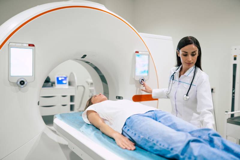 A radiologist taking a patient to the PET scanner inside an Scan room.