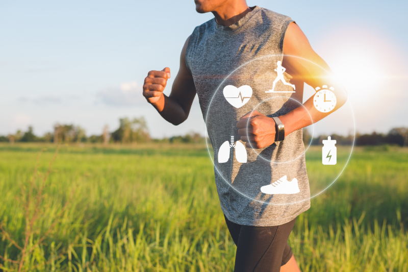 Image of a man wearing a smart watch doing jogging in an outside environment covered with greenery.
