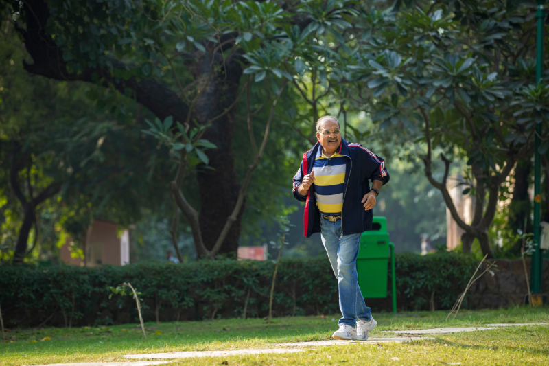 A healthy looking old man running or jogging at park.