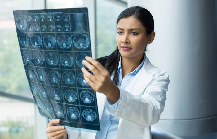 A female doctor examines the x ray results of a patient.