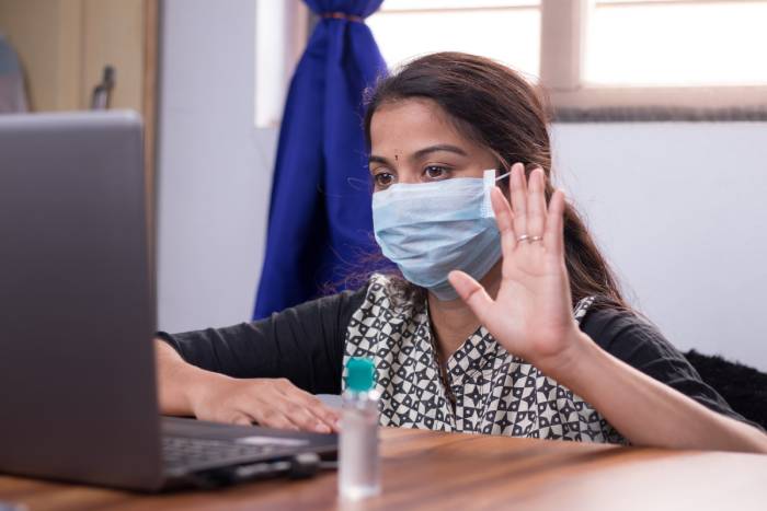 A sick young girl wearing a mask is talking to a doctor via video conference.