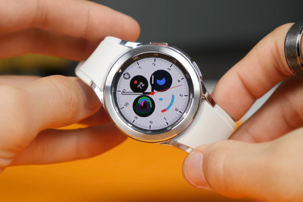 Close up view of  two hands holding a white strapped smart watch with a and silver dial.