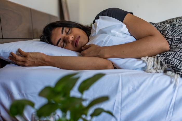 A woman taking an afternoon nap lying on her bed.