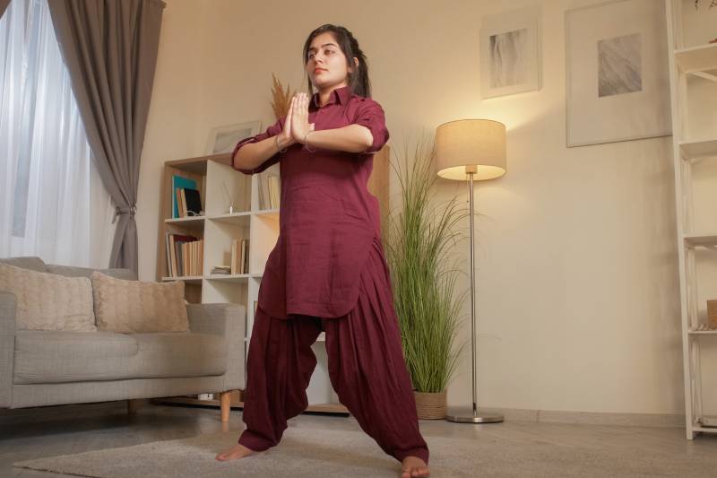 A young woman practicing yoga in a living room.