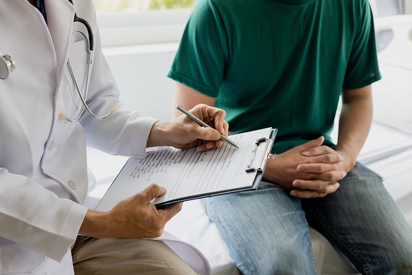 A mental health care professional consulting with a patient and making notes on a clipboard during a healthcare appointment.
