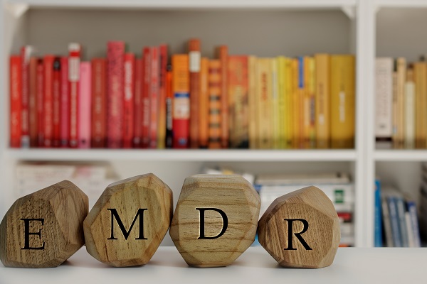 The letters EMDR are written on irregular wooden blocks, representing the treatment for post-traumatic stress disorder (PTSD).