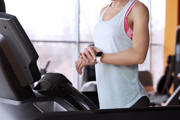 A young woman monitoring her training stats with a fitness tracker at the gym.