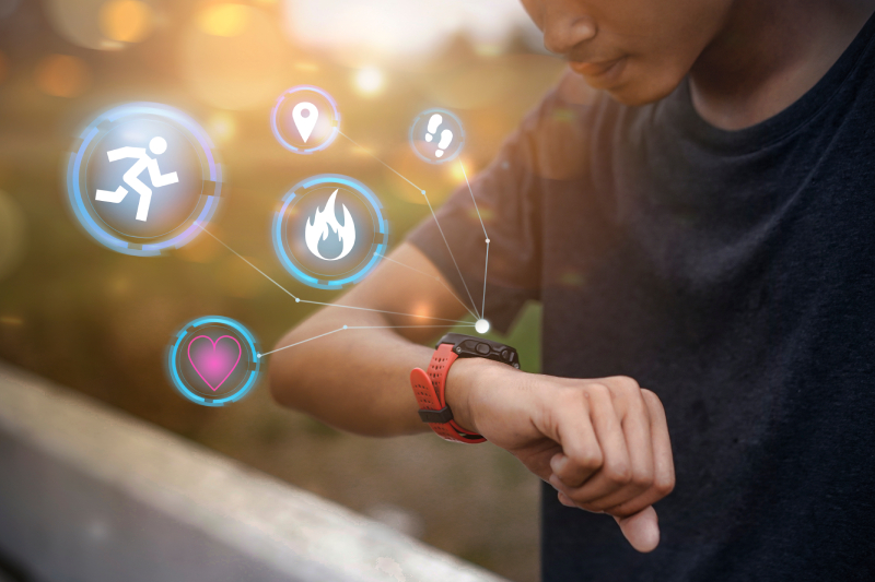 A young man checks his running distance, heart rate, and fitness metrics on a smartwatch with a holographic interface.
