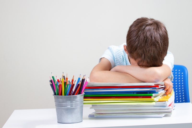 A boy lying on a pile of school books, illustrating the struggles of learning challenges and the importance of parental support.
