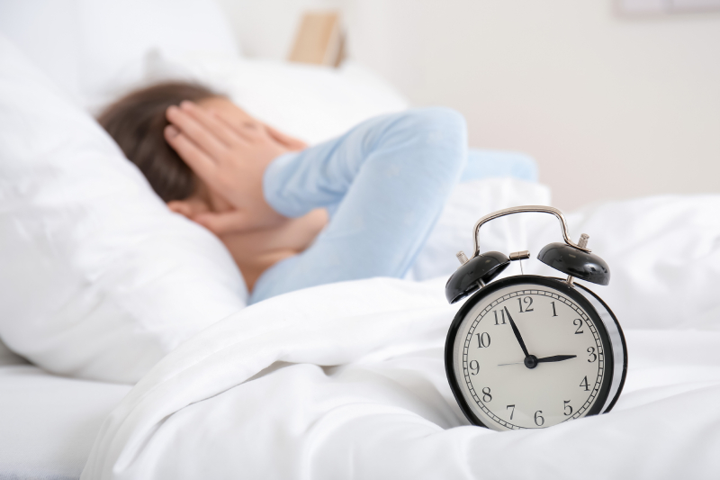 Alarm clock resting on a child’s bed, symbolizing how stress-related sleep disorders harm health and interfere with everyday life.