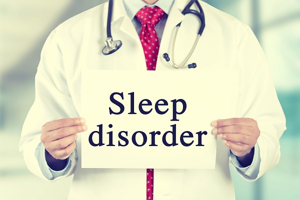 A medical professional holding a white card with "sleep disorder"text in a hospital environment.