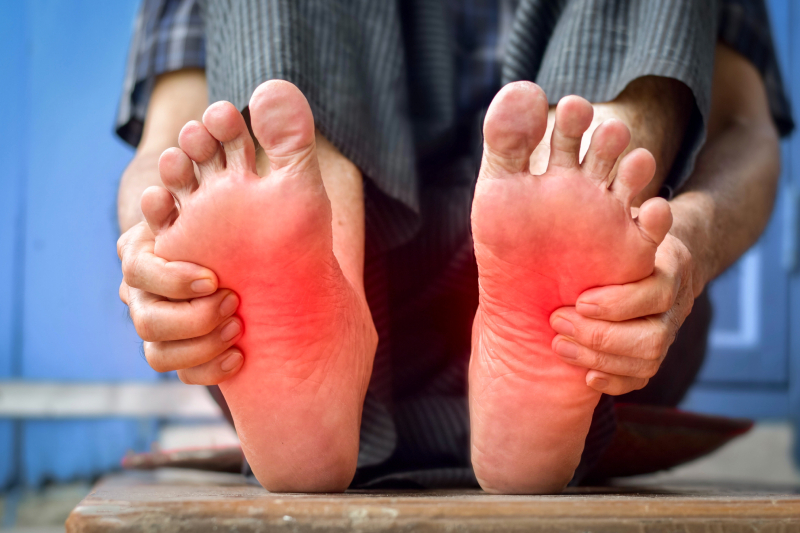 A person holding feet with red discoloration symbolizes diabetic foot pain and its impact on daily life.