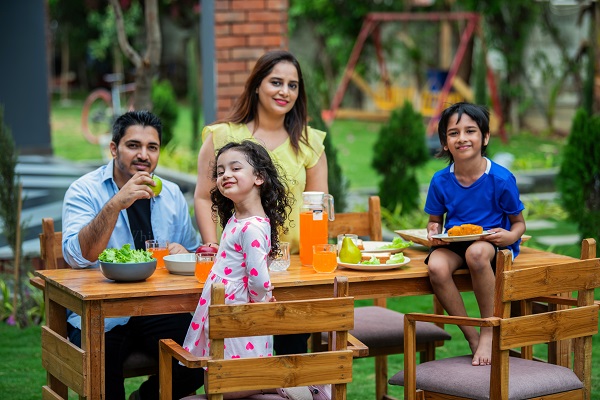 A family of four dining outdoors, connecting lifestyle factors like diet with daily routines.
