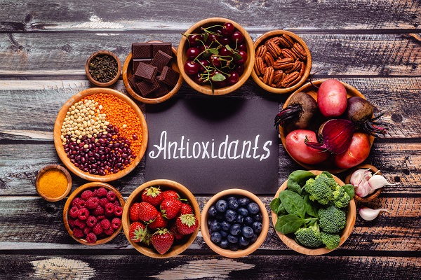 Antioxidants' written on a slate, surrounded by antioxidant-rich foods, symbolizing their role in heart health.