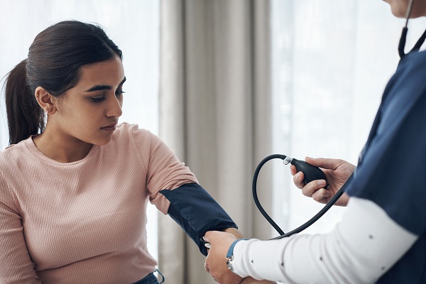 A healthcare professional checking a female patient’s blood pressure, representing hypertension.