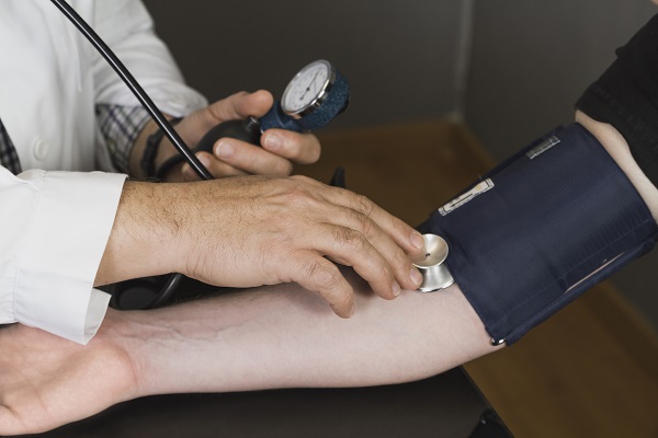A blood pressure monitor, ECG report, and a red heart symbolizing signs of high blood pressure.