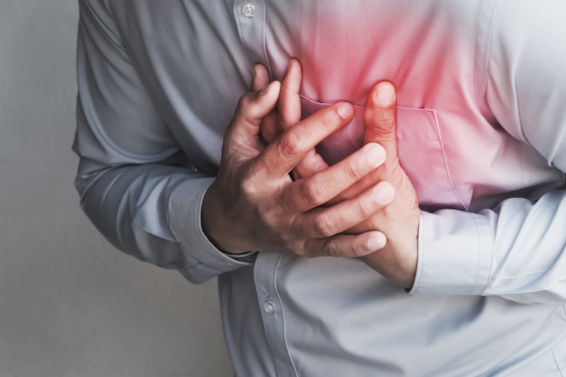 A man holding his chest in pain, representing symptoms of a silent heart attack.