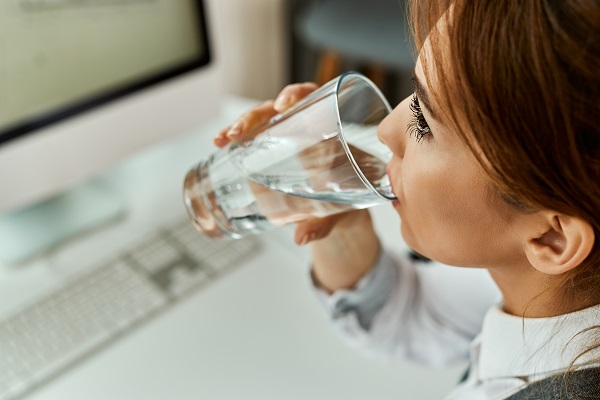 A woman sipping pure filtered water, emphasizing the importance of proper hydration before conducting a test.