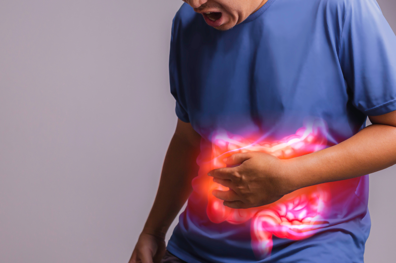 A person holding their stomach with a red glow, symbolizing abdominal pain and gut health.