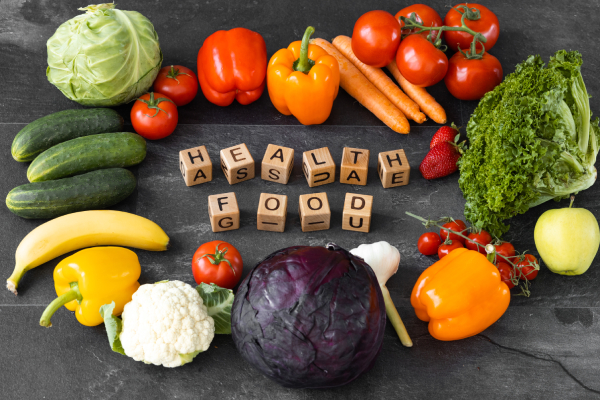 Fresh vegetables and fruits surround blocks spelling "HEALTHY FOOD" on a dark surface, emphasizing a prediabetes meal plan for blood sugar control.