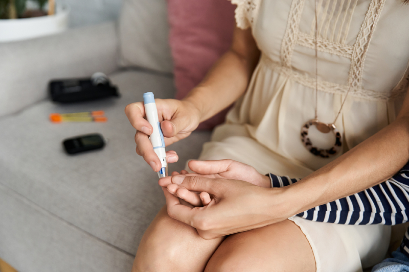 A caring mother gently tests her child's blood sugar levels with a glucometer in the comfort of their family living room.