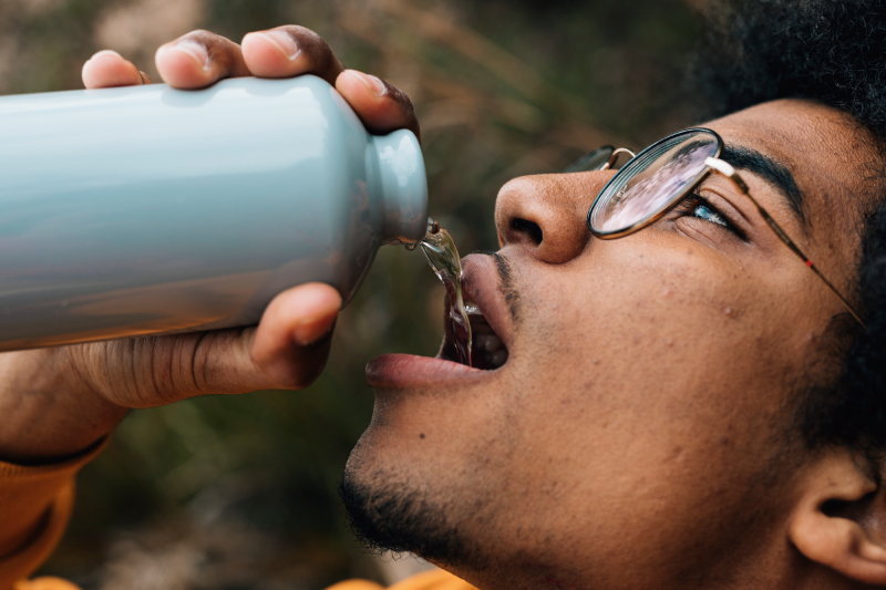 A man drinks water from a bottle, symbolizing how rising blood sugar levels cause dehydration and excessive thirst.
