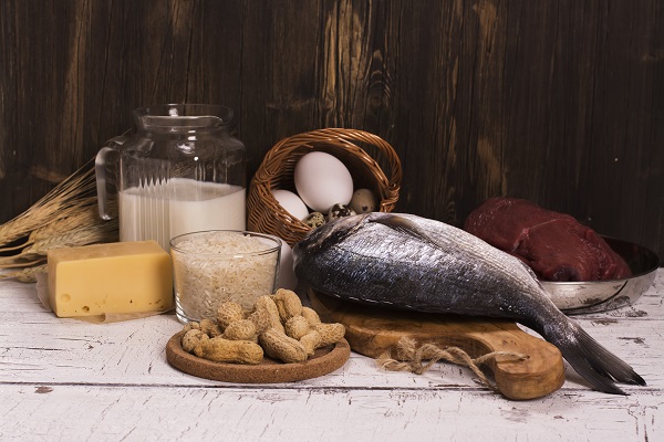 Foods rich in vitamin D, including fish, meat, eggs, cheese, milk, and nuts, neatly arranged on a wooden surface.