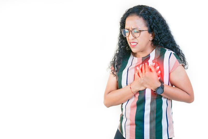 A woman clutching her chest in pain, representing symptoms of women's heart disease.