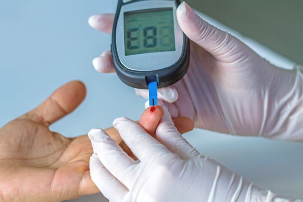 A person tests blood sugar with a glucose meter, pricking their finger for a drop of blood, highlighting the contrast with a CGM's painless monitoring.