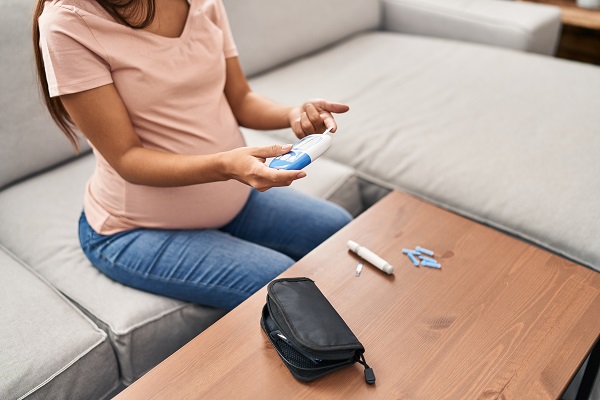 A pregnant woman measuring her blood sugar at home with diabetes testing tools, symbolizing gestational diabetes tests.