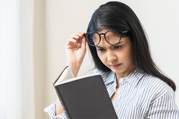 A woman struggling to read a text message on her smartphone due to blurred vision, a possible sign of insulin resistance.