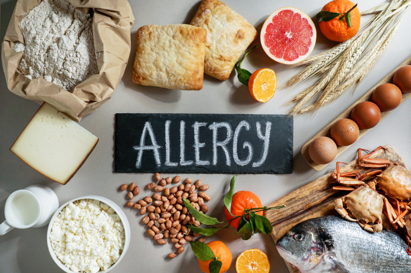 Common food allergens like nuts, dairy, eggs, wheat, seafood, and citrus arranged around an 'ALLERGY' sign.