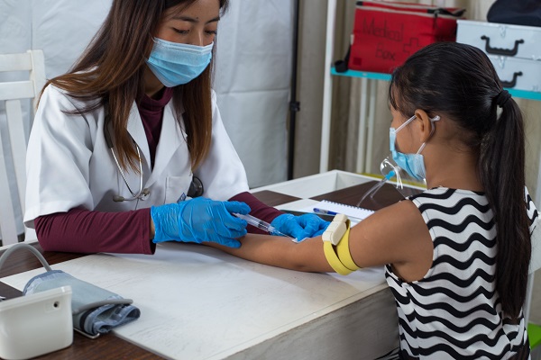 A professional drawing blood from a young girl, emphasizing staying calm during the test.