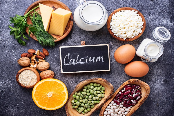 Calcium text on a slate with calcium-rich foods, representing the importance of diet and exercise for bone health.