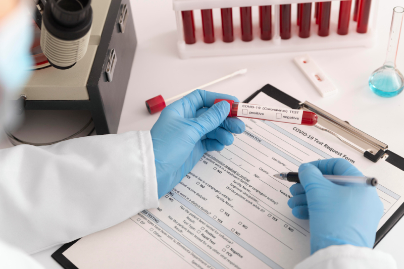 A doctor holding a COVID-19 test tube over a test request form, emphasizing early diagnosis.