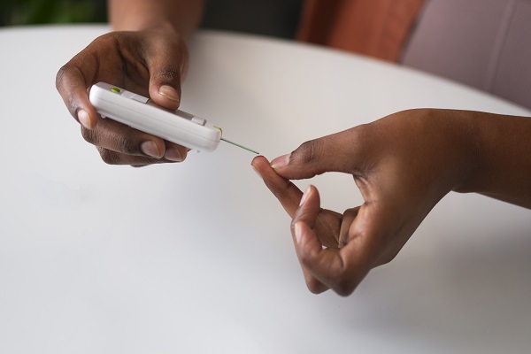 A person checking glucose levels, highlighting the best finger for blood sample collection.