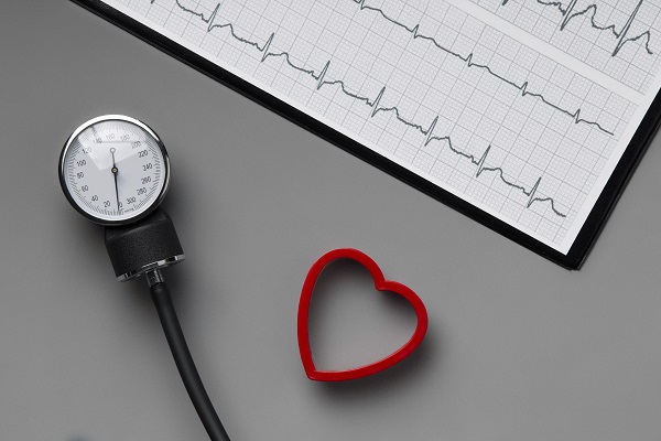 A blood pressure kit with a red heart and ECG, symbolizing the link between irregular heartbeat, arrhythmia, and high blood pressure.