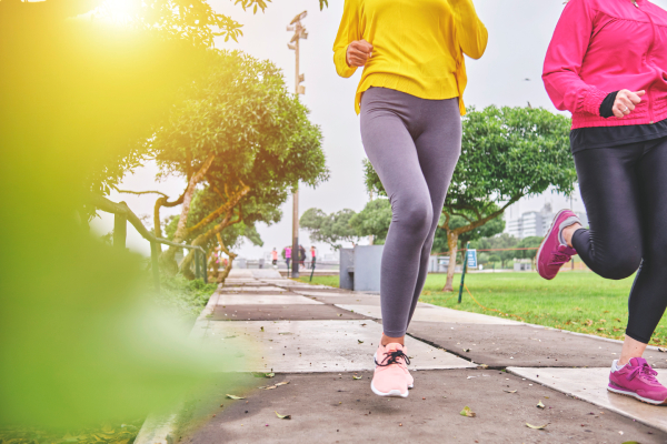 Two fit young women jogging or running outdoors during a morning workout to maintain a healthy lifestyle.
