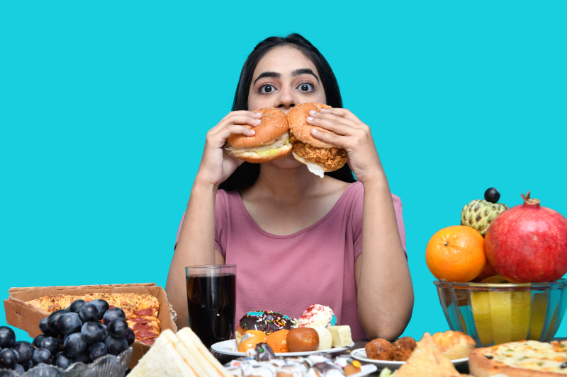 woman holding two burgers amid fast food, symbolizing polyphagia, or extreme hunger.