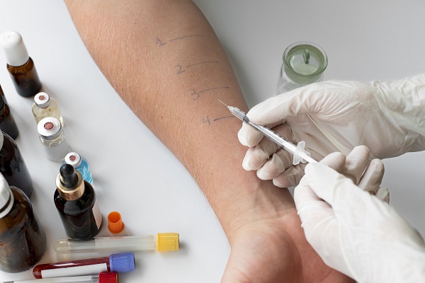 Healthcare professional injecting a numbered site on a patient's arm for a skin allergy test.