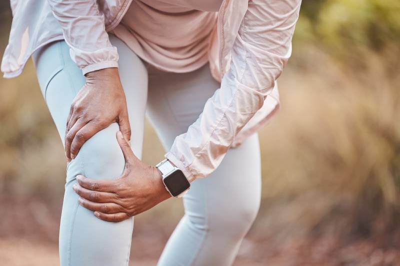A person holding their knee during exercise, highlighting the added joint pressure from winter weight gain.