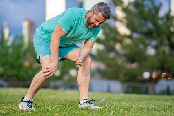 An elderly man outdoors with knee pain, highlighting the need to reduce swelling before exercising with arthritis.