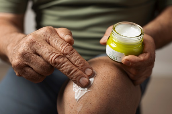 A man applying cream to his knee, illustrates how topical treatments can relieve arthritis pain.