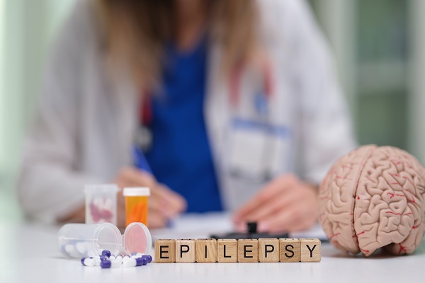 Wooden block labeled 'EPILEPSY', pills, and model symbolizing neurological disorders.