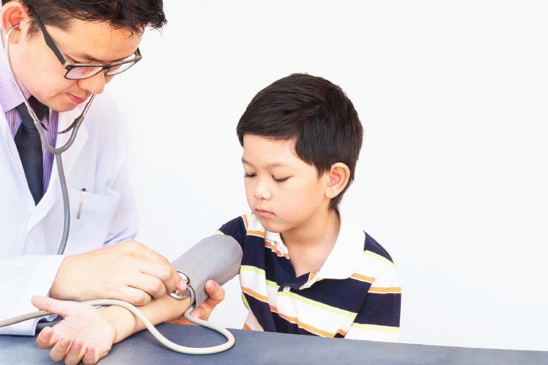 A doctor checking a child’s blood pressure, indicating concern for hypertension.