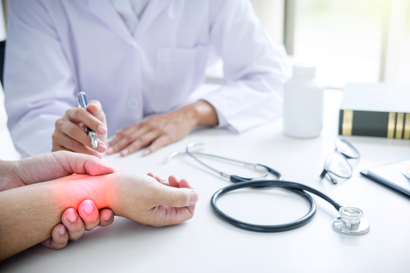 A doctor consulting a patient with wrist pain highlighted in red, stressing the need to identify joint pain causes.