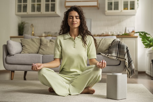 A woman sitting calmly at home with her eyes closed, focusing on her breath as she begins mindfulness practice.